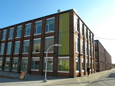 A three storey building with green accents nearest the corner.