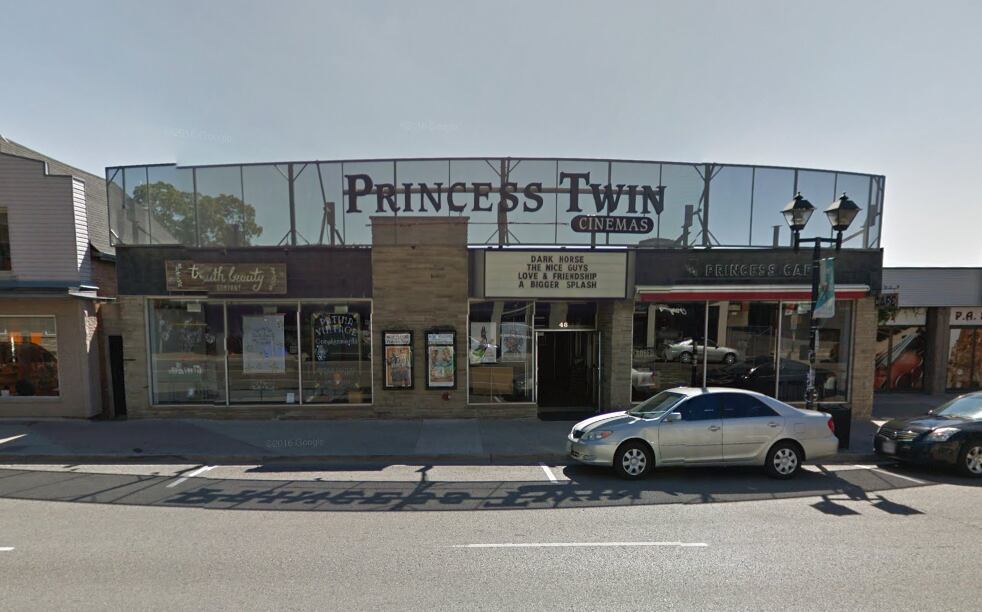 The front of the Princess Twin Cinema with cars parked on the street in front